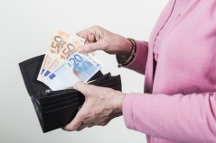 Eine Frau nimmt mehrere Geldscheine aus der Geldbörse