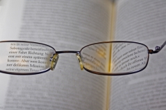 Durch die Gläser einer Brille lässt sich der Text eines Buches erkennen.
