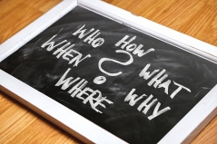 Eine Tafel mit den Fragewörtern How, Who, What, When, Why und Where